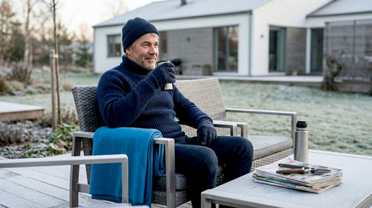En svensk villaägare njuter av sommarvärmen i sin trädgård, bekvämt tillbakalutad i en loungestol av aluminium.