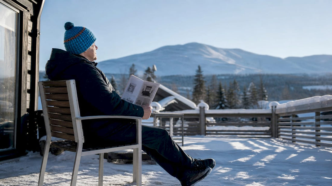 En person sitter på en rejäl utestol omgiven av vinterlandskap.