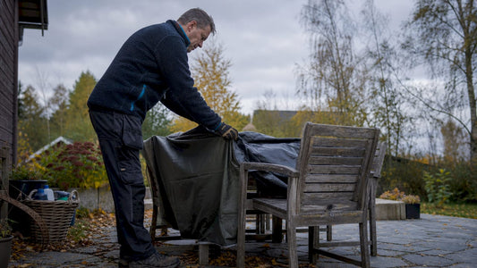 En person som täcker över utemöblerna inför hösten.