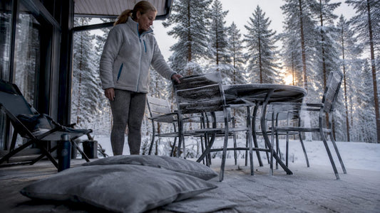 En kvinna ser över sina utemöbler på gården en solig dag i Norrland.